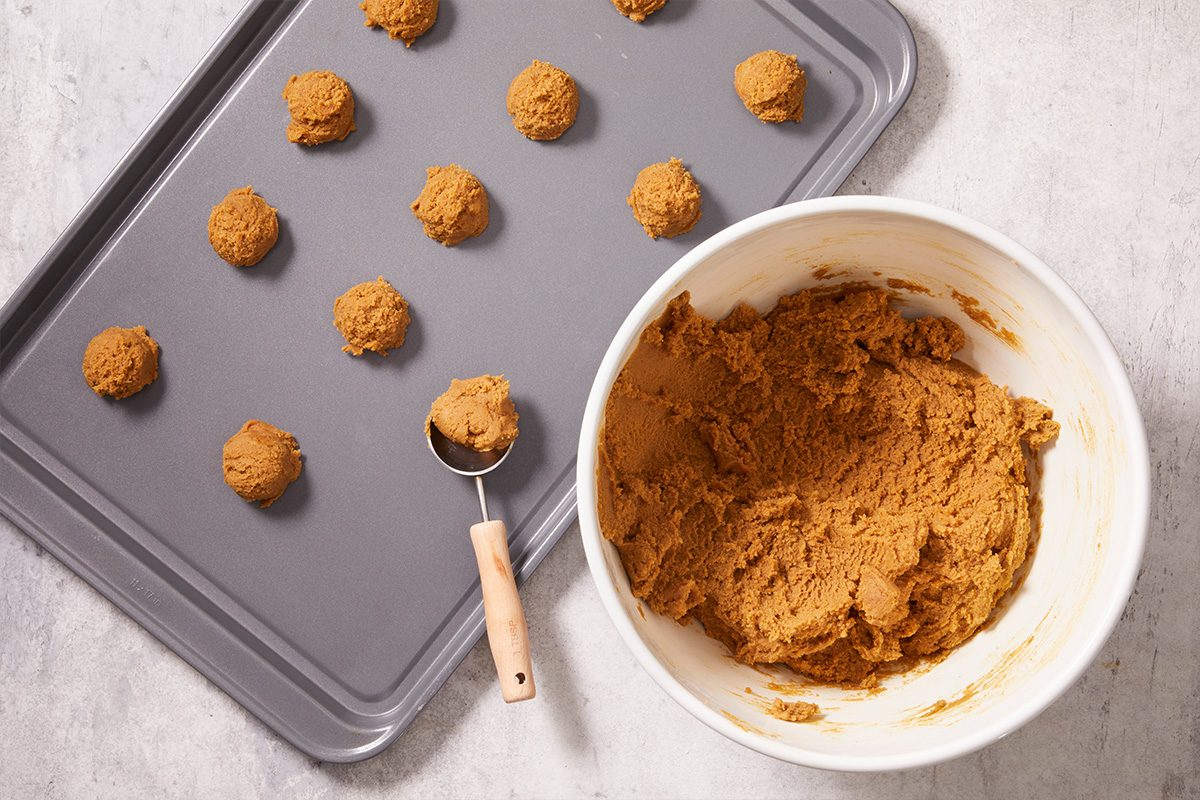 Overhead shot of cookie dough scooped and placed onto a baking sheet lined with parchment paper, ready to bake.