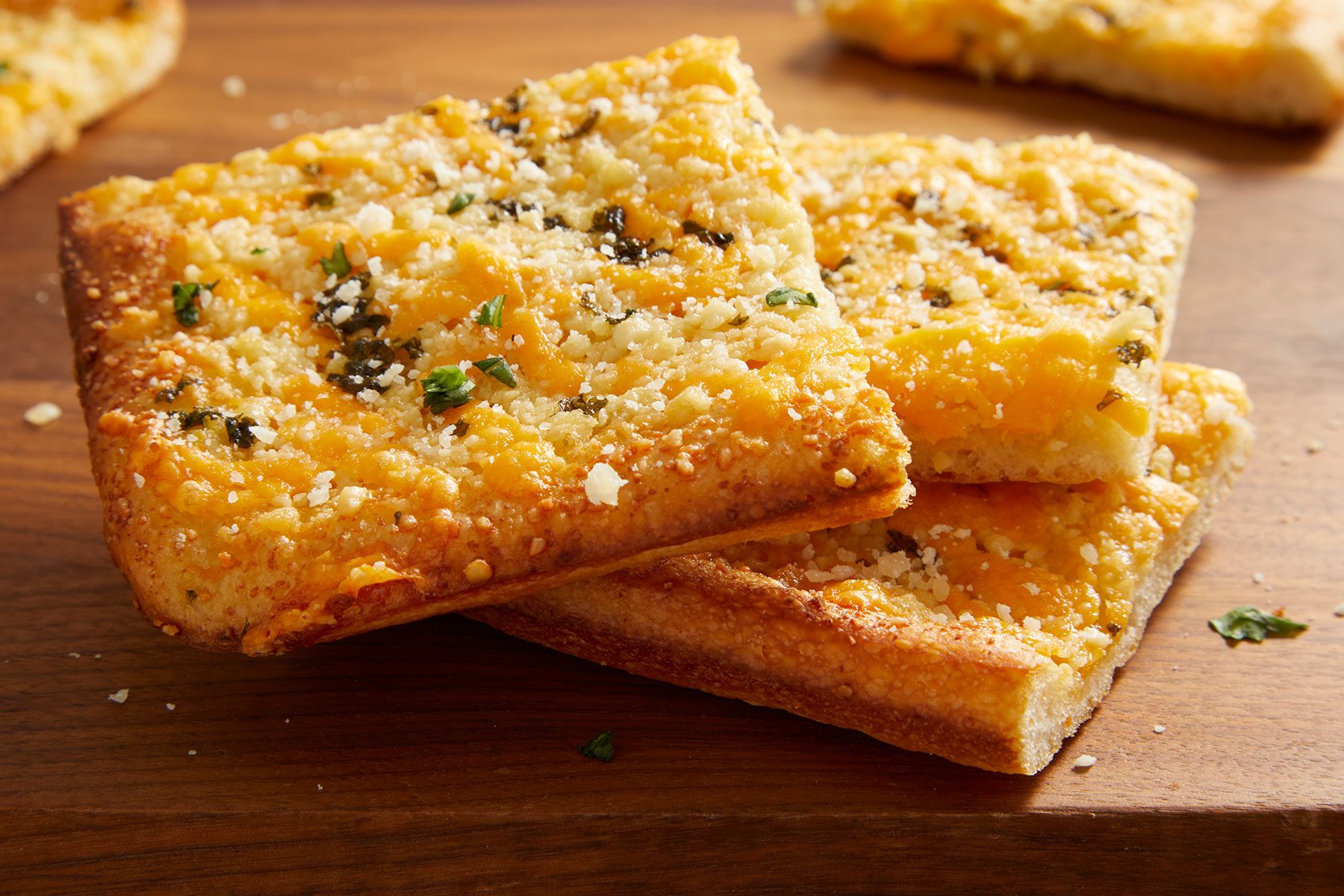Garlic Cheese Flatbread squares on top of each other on a wooden table.