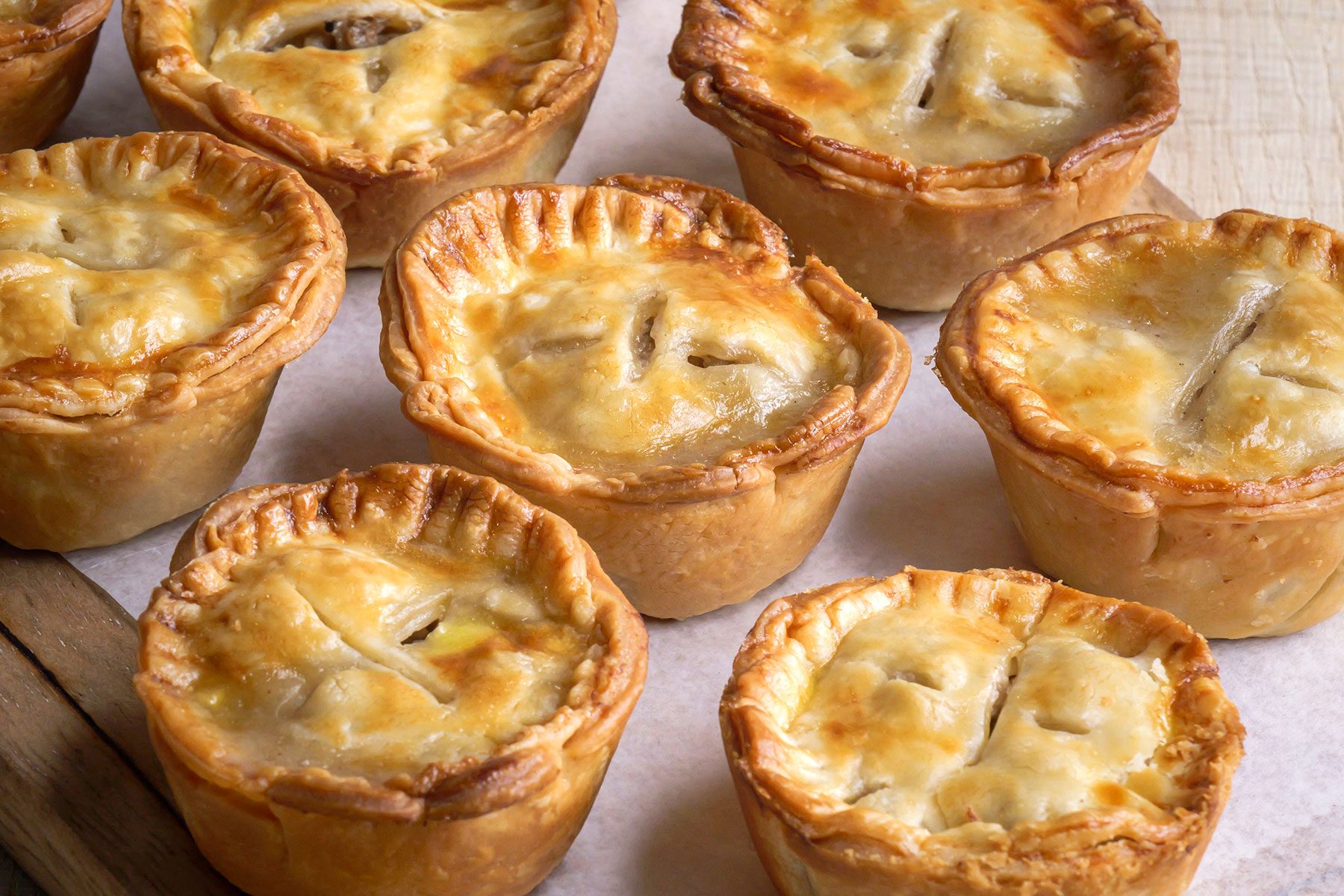 Front view of Mini Pork Pies baked and kept on a wooden board with lining sheet.