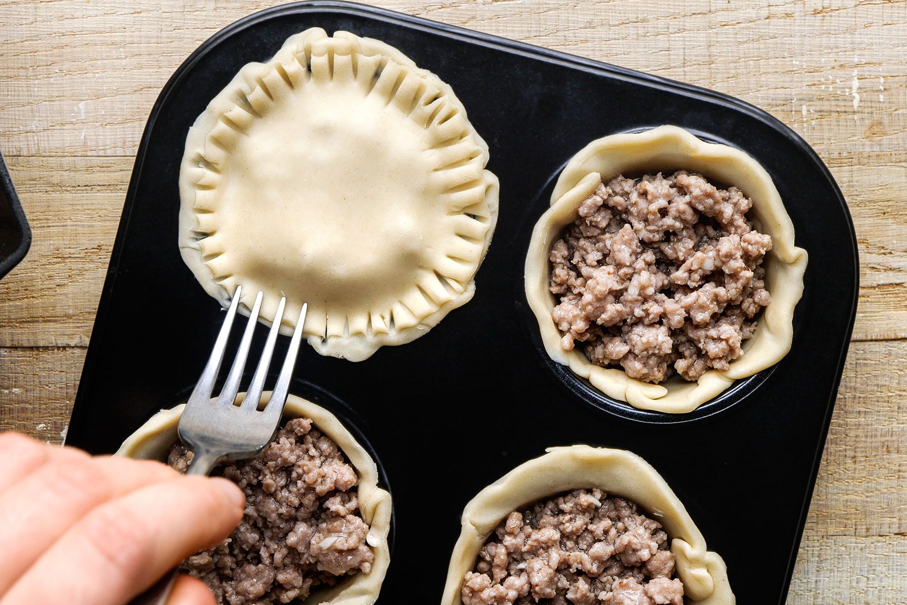 Filling each bottom crust with 3 tablespoons of the cooked pork mixture, covering with the smaller dough circles and pressing edges with a fork.