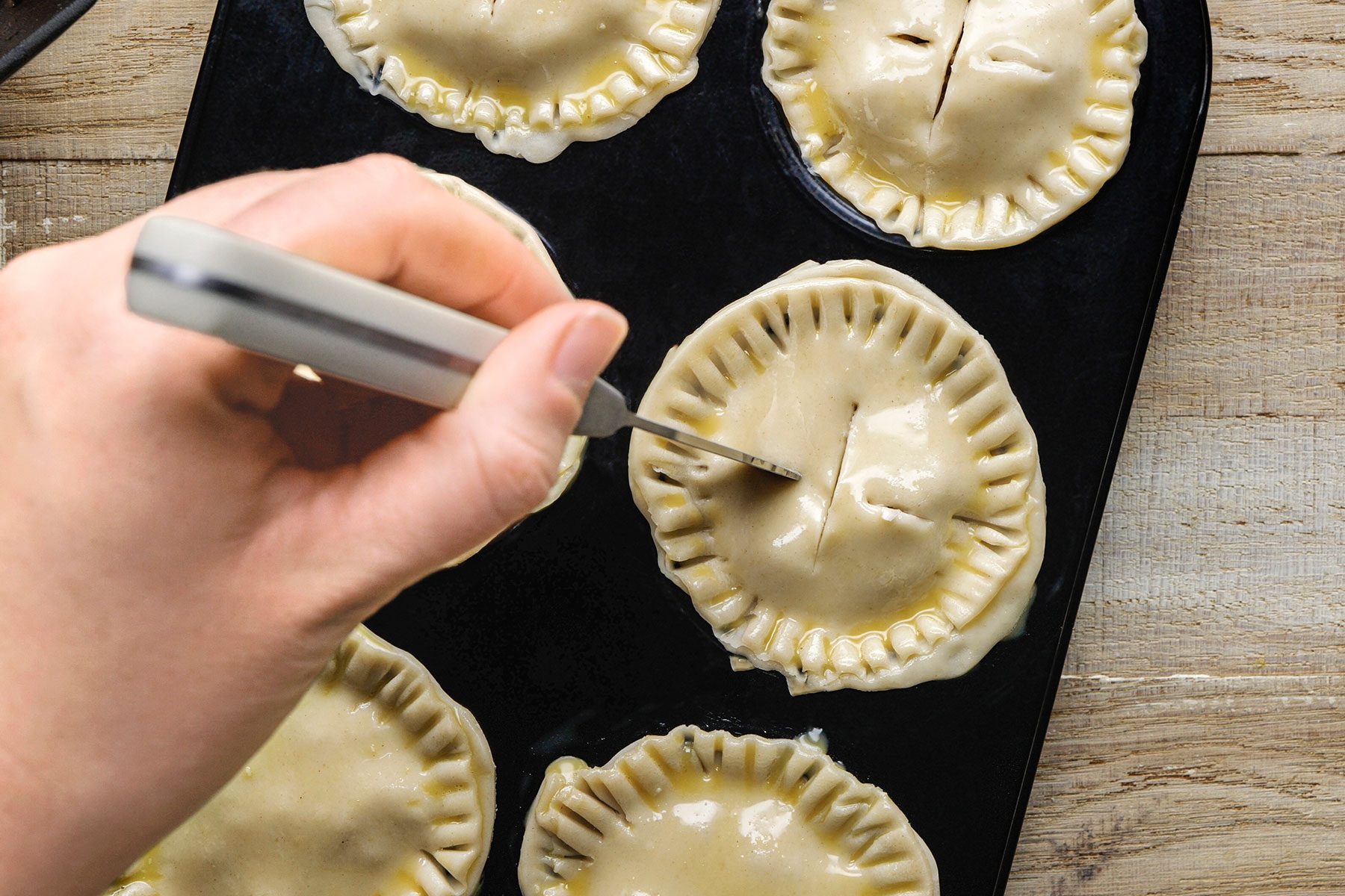 Cutting slits in the top pie crusts with a knife.