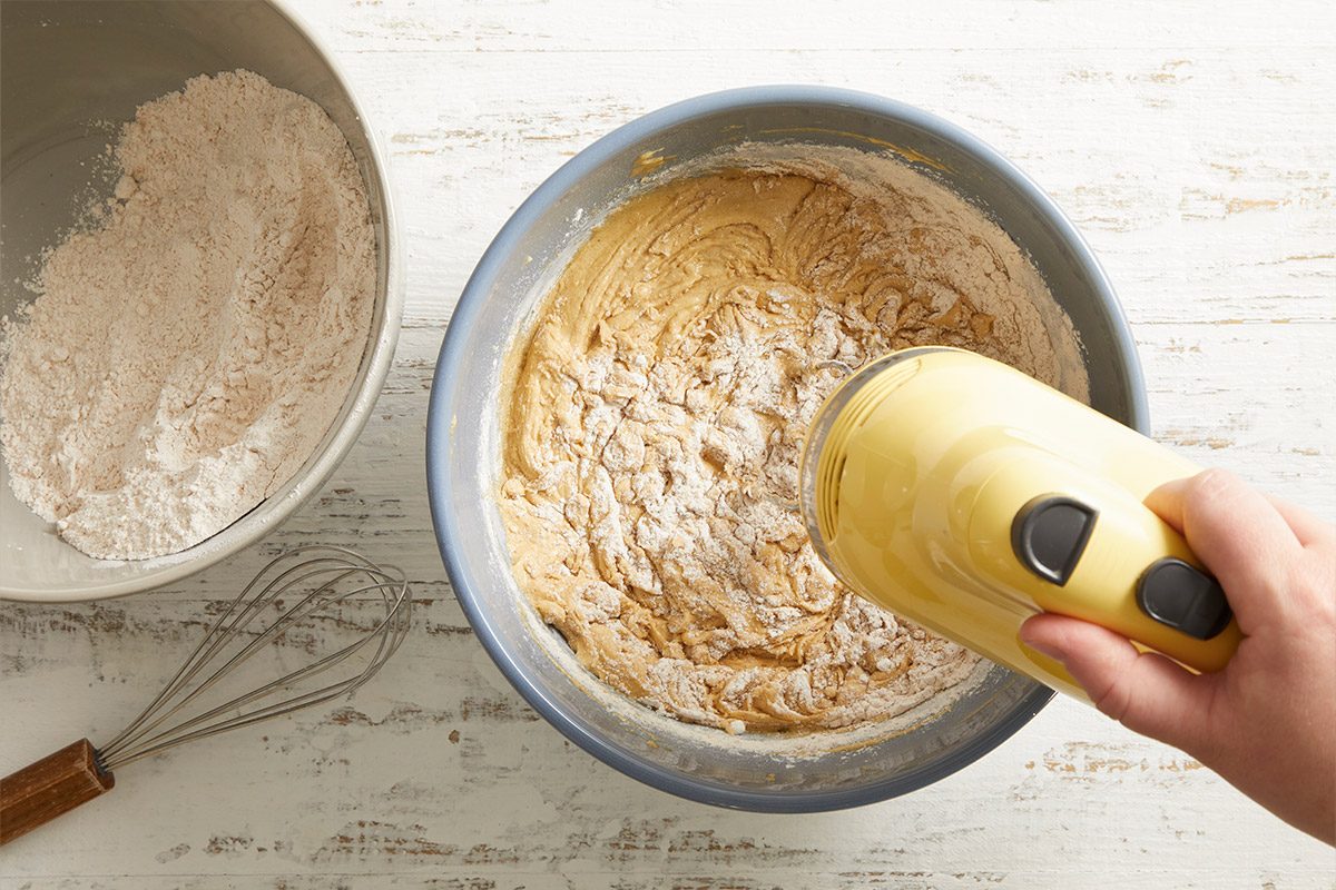 Overhead shot of flour being added to the creamed butter and sugar mixture while mixing with a hand mixer.
