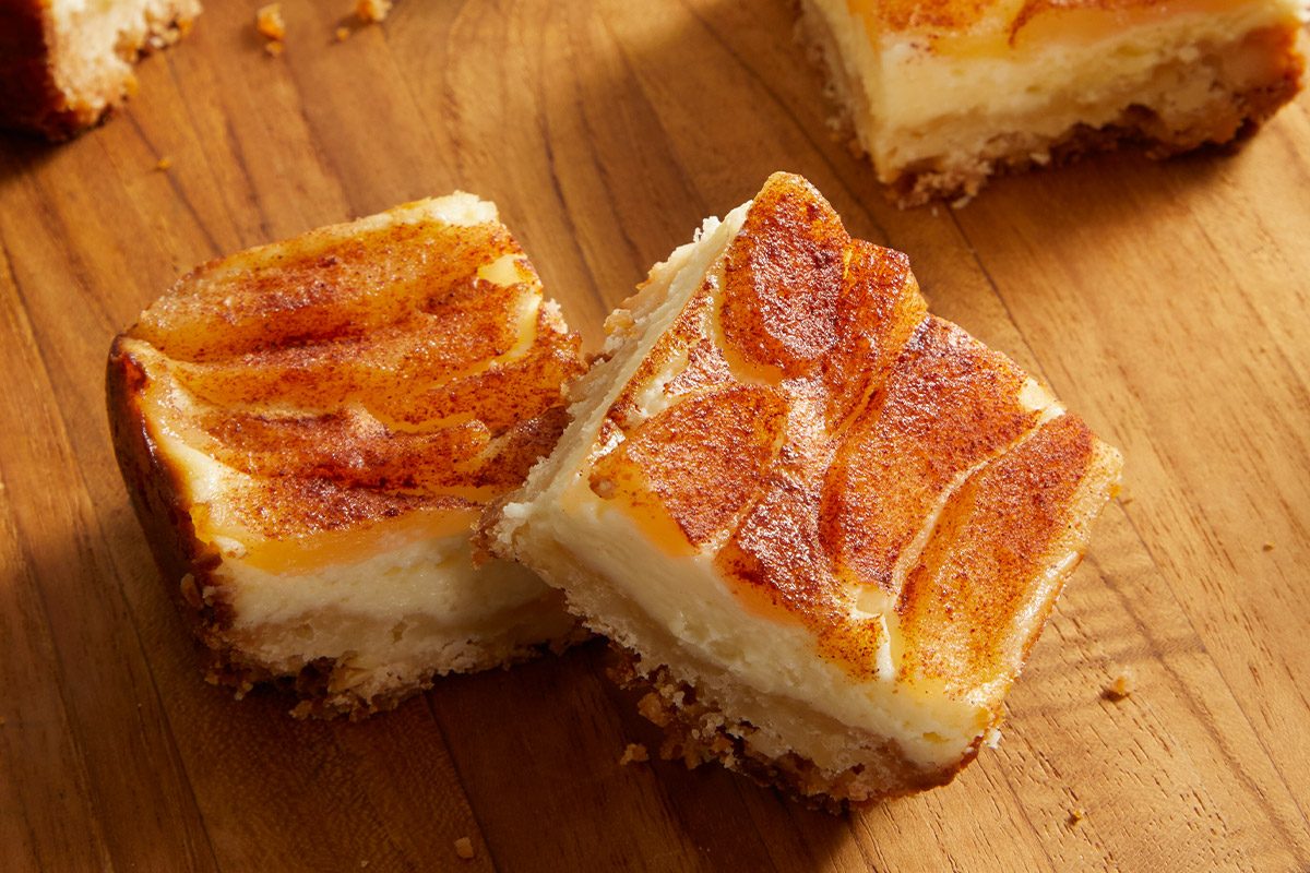 Vertical shot of Pear Custard Bars sliced into squares and stacked on a wooden board