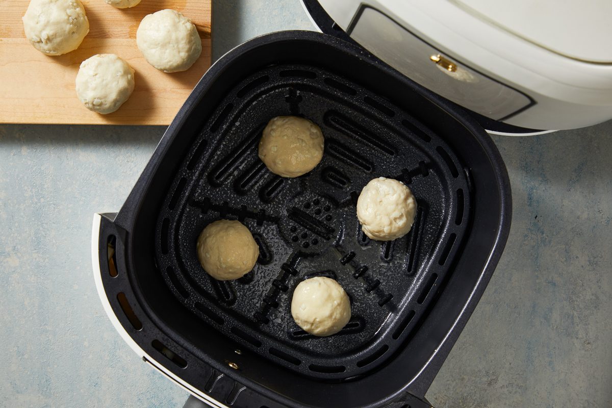 doughnuts placed in a single layer onto a greased air-fryer basket
