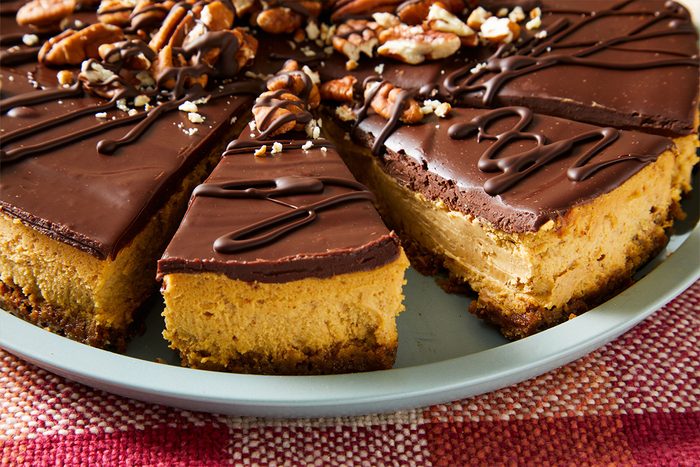 3/4 Close-up of the sliced Gingerbread Cheesecake, highlighting the smooth filling, thick crust, and glossy chocolate topping with pecans.