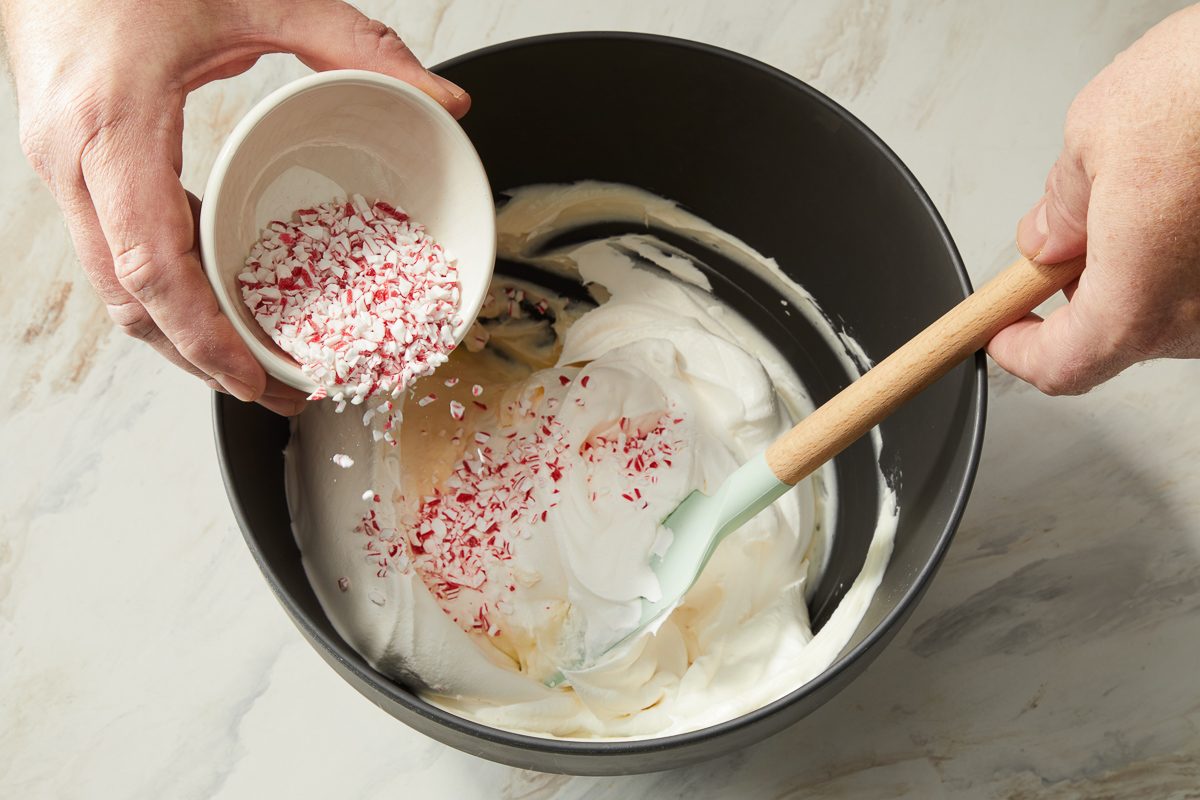 Peppermint candies being added to whipped topping, sugar and cheese mixture